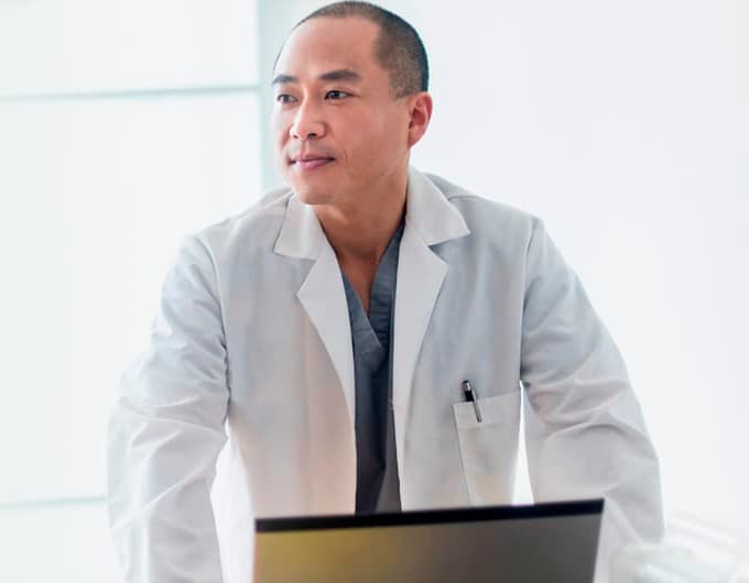 A male doctor in a white coat is staring intently to the left.